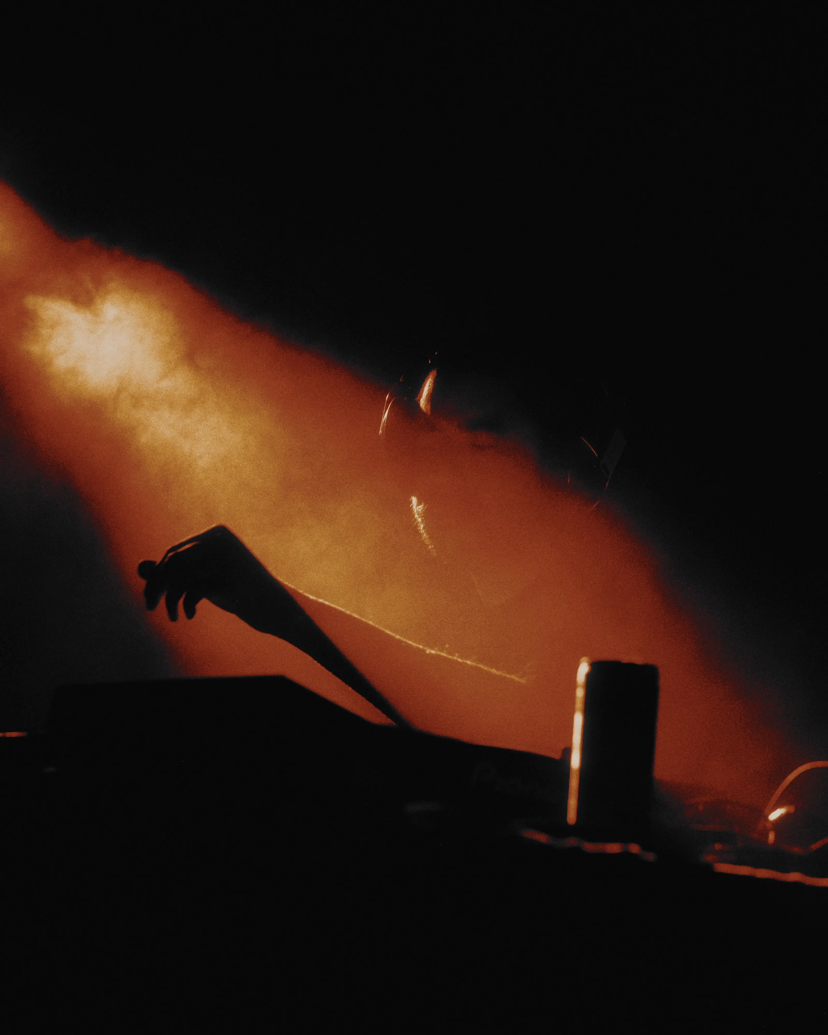 A hand reaching into a beam of red stage smoke, with the Cine 500T look